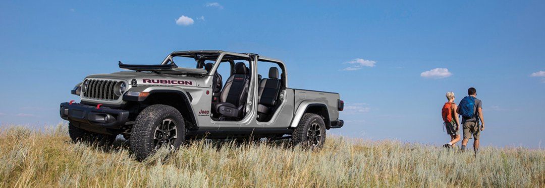 A Jeep Gladiator parked in the tall grass of a field.