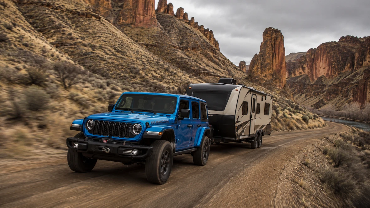 Blue Jeep Wrangler 4xe towing an off-road trailer.