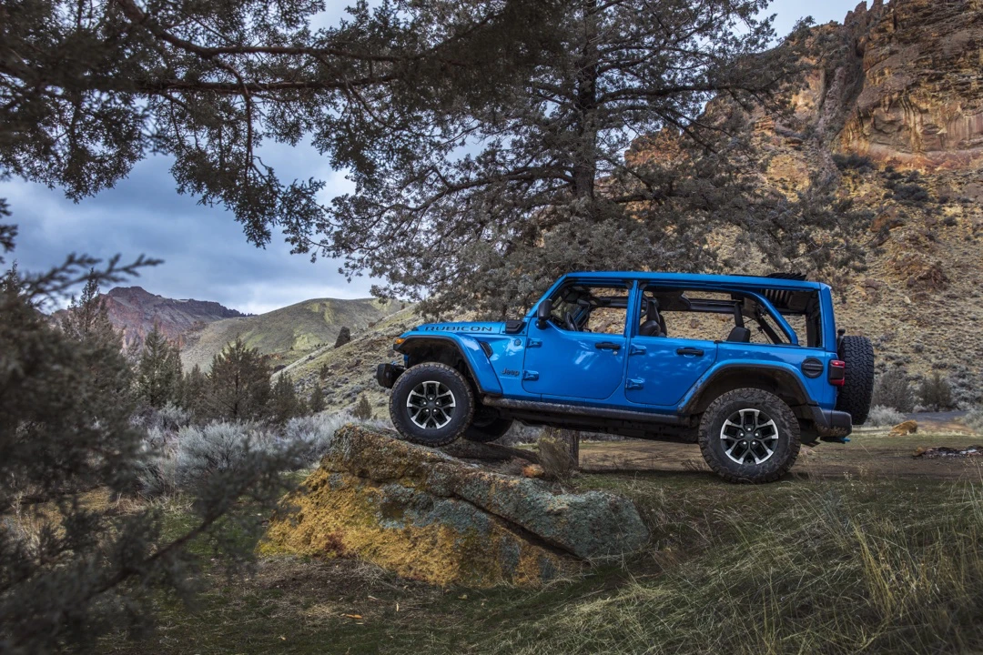 Blue Jeep Wrangler 4xe on an off-road trail.