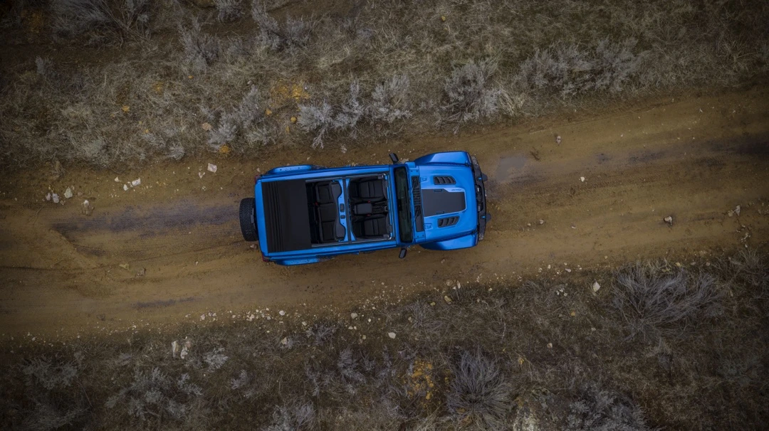 Aerial view of a blue Jeep Wrangler 4xe on a road.