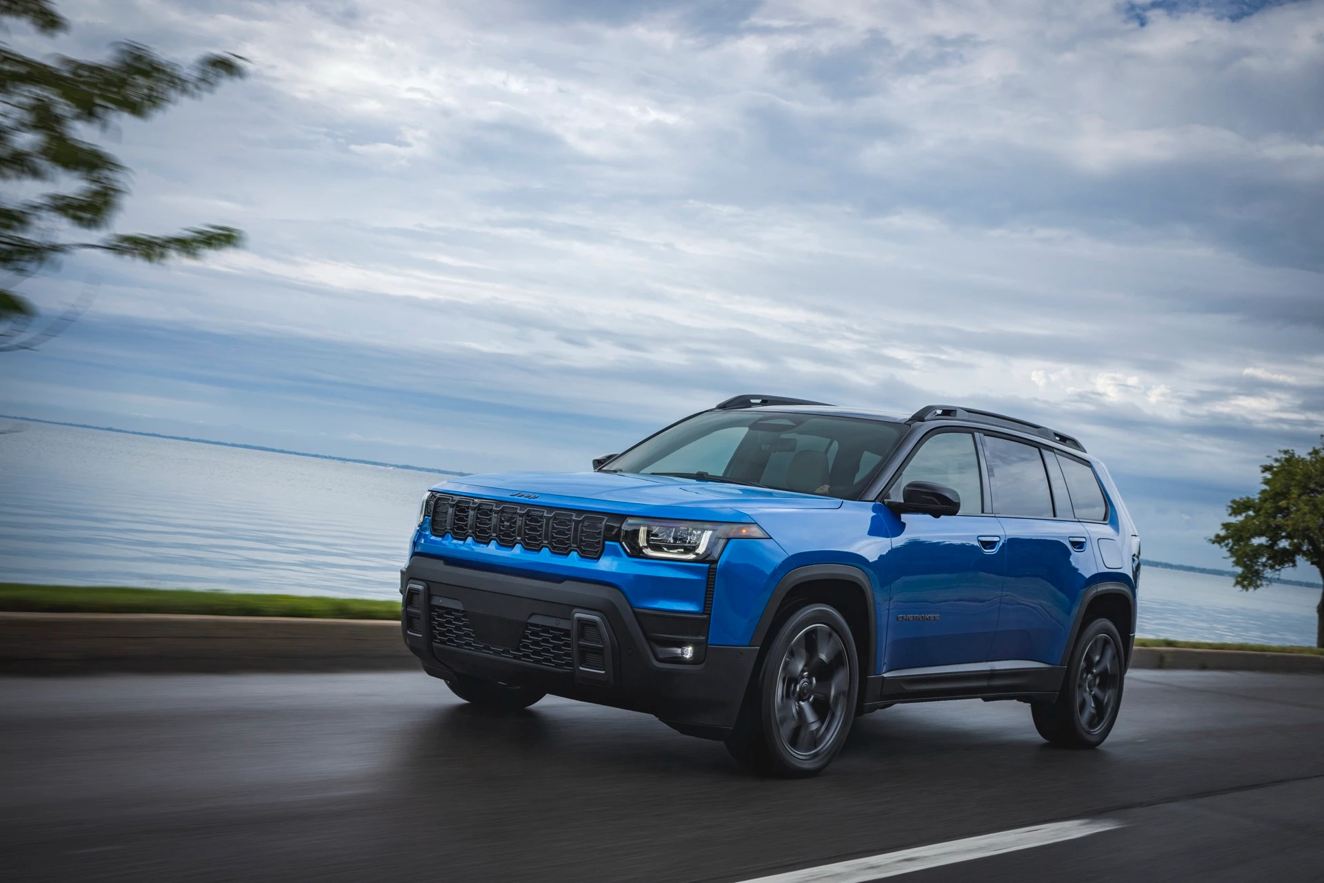 Jeep Cherokee 2026 bleu roulant au bord de l&rsquo;eau.