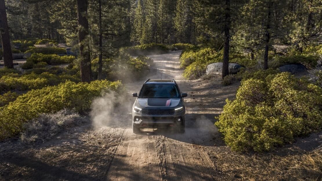 Le jeep Grand Compass qui roule sur un chemin dans une forêt.