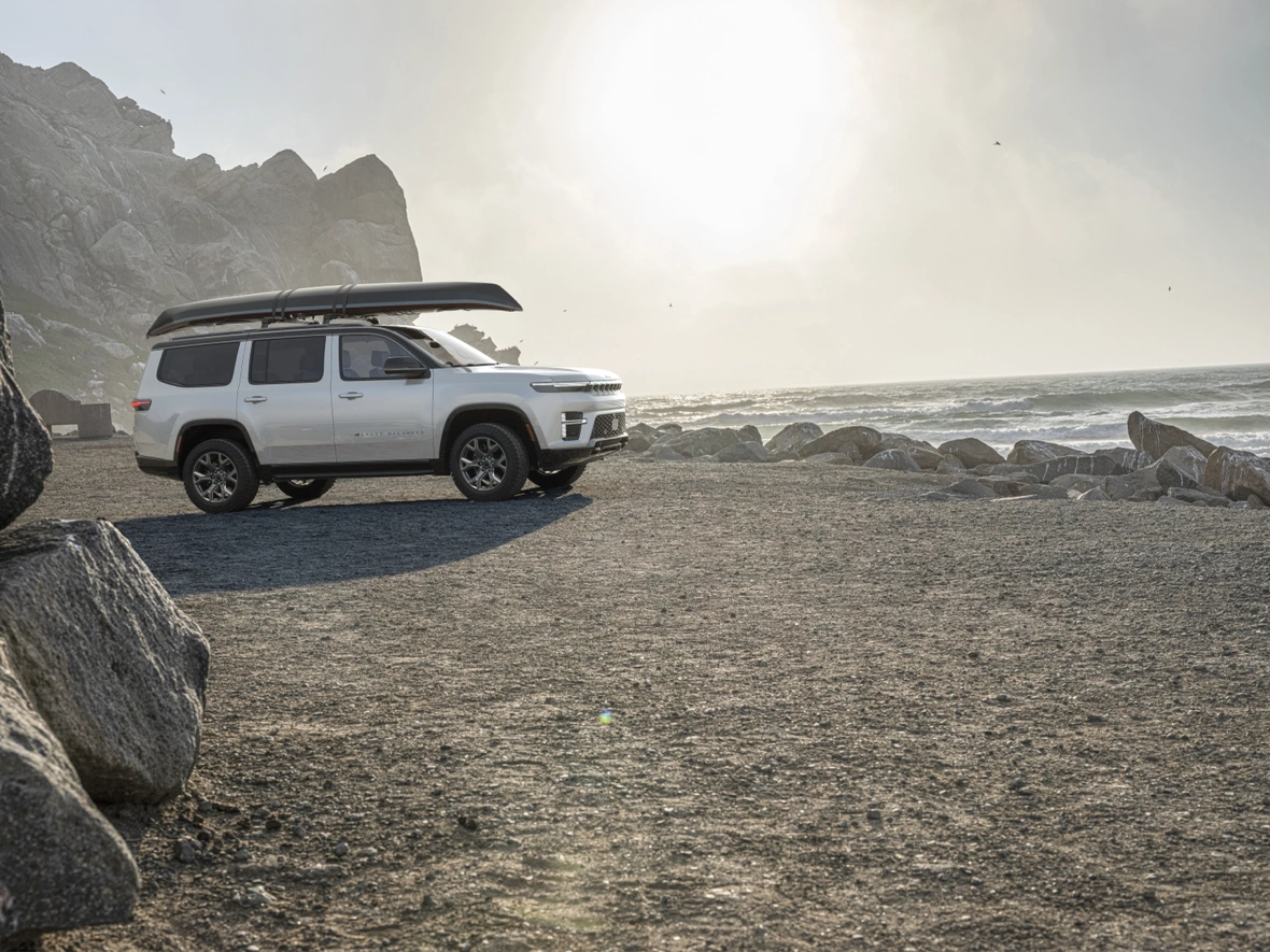 Jeep Grand Wagoneer 2026 blanc avec un canot pr&egrave;s de la mer.