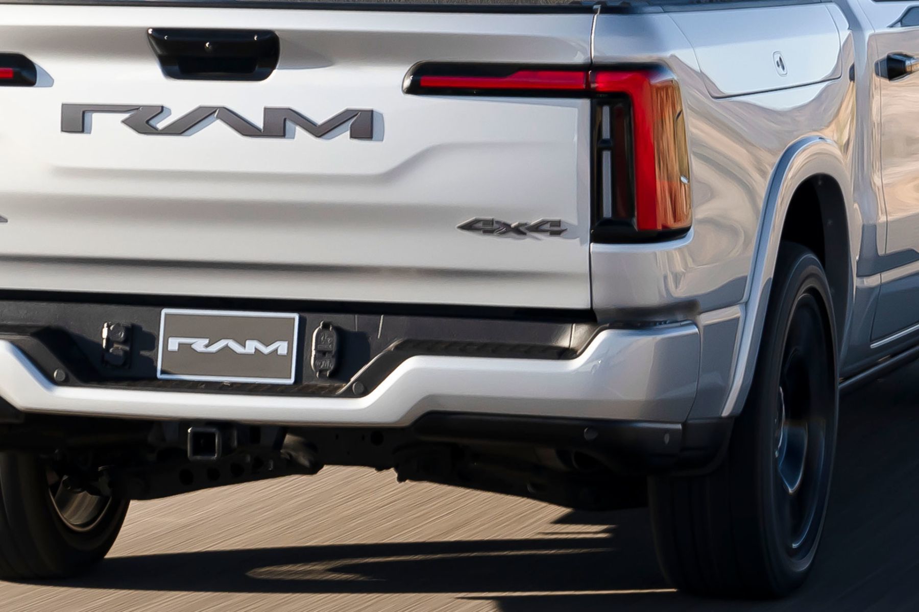 Rear close-up of the white 2026 RAM 1500 Ramcharger showing the RAM badge and 4x4 emblem.
