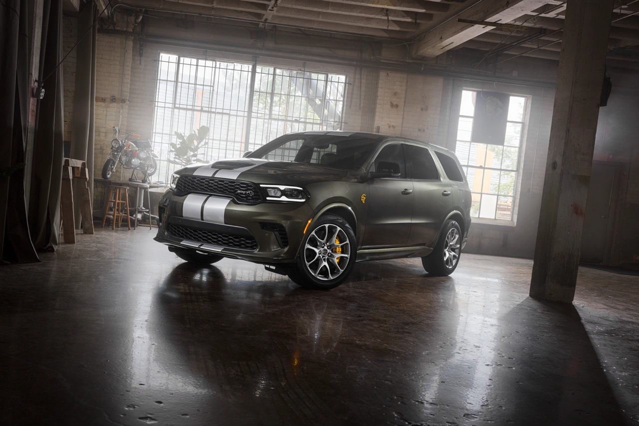 Black 2026 Dodge Durango with white racing stripes front three-quarter view parked inside an industrial garage.