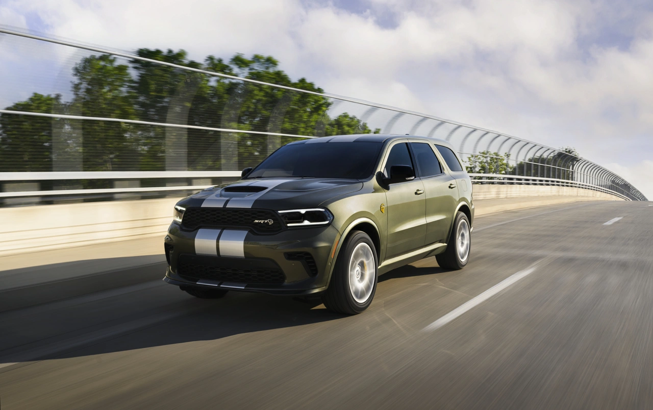 Black 2026 Dodge Durango with white racing stripes driving on a modern bridge.