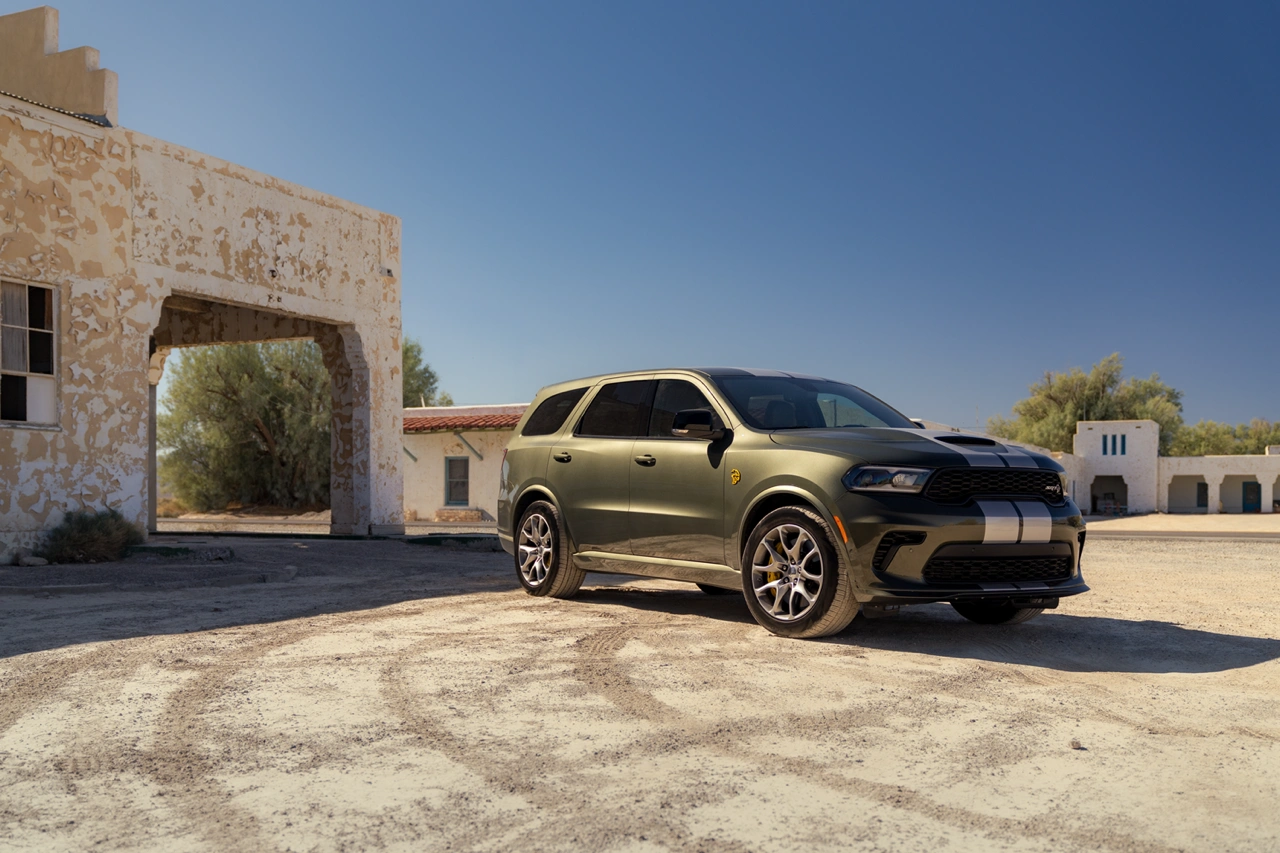 Black 2026 Dodge Durango front three-quarter view parked in front of a stone building in a sunny setting.