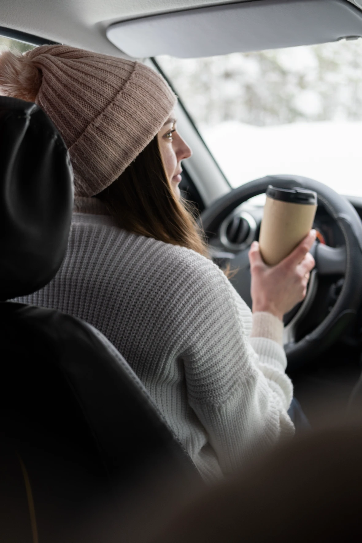 Driver behind the wheel of a hybrid car in winter.