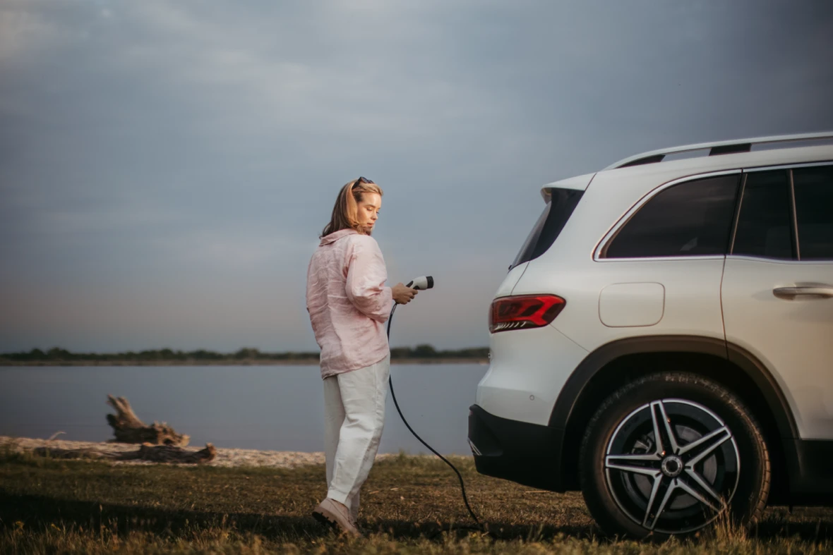 Charging a plug-in hybrid SUV near a lake.