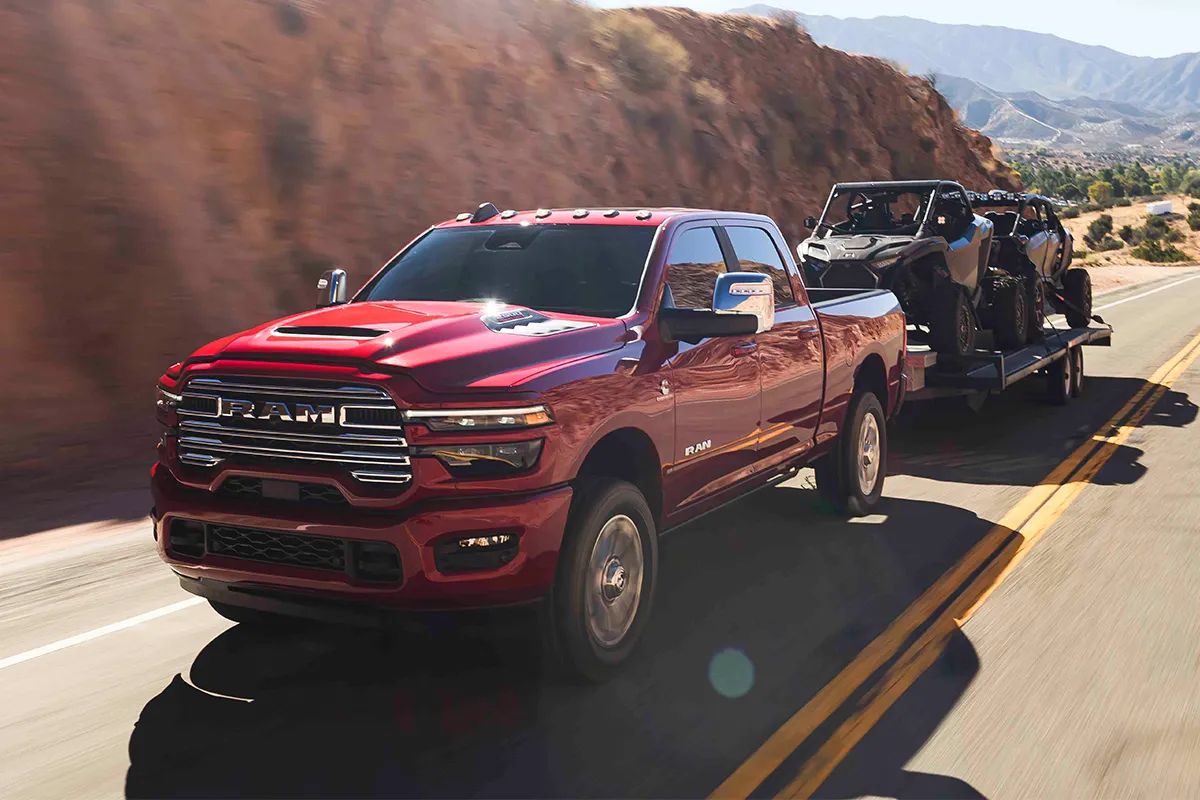 Ram 2500 2026 rouge remorquant une roulotte avec un v&eacute;hicule hors route.