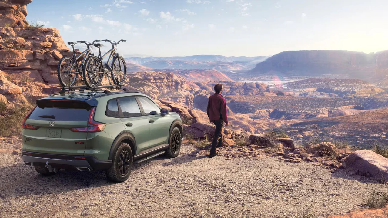 Honda CR-V 2026 vert avec des vélos sur le toit dans un paysage montagneux.