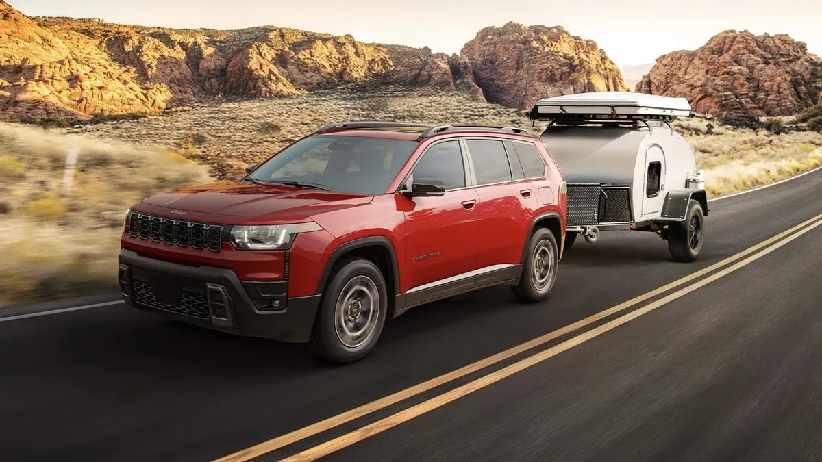 Jeep Cherokee 2026 rouge remorquant une petite roulotte.