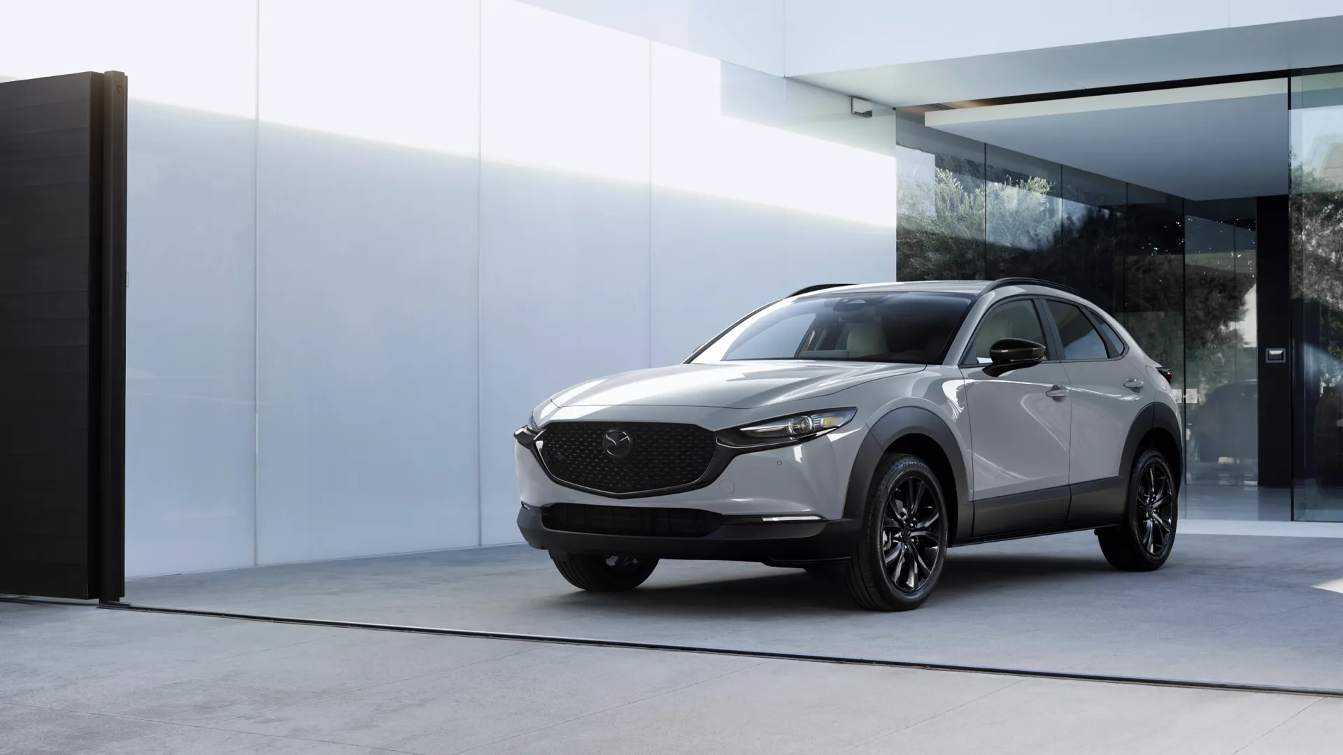 Mazda CX-30 2026 gris stationné devant un bâtiment moderne