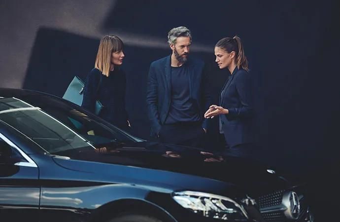 A couple chatting near a Mercedes-Benz
