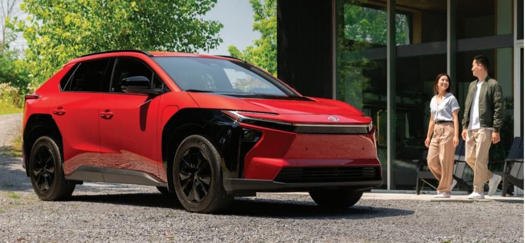A smiling female salesperson and a male customer look at a clipboard together inside a bright car dealership showroom.