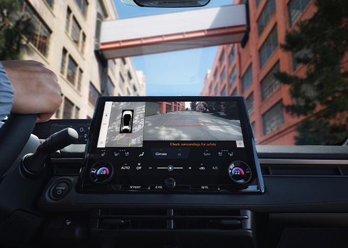 The rear view of a red sedan parked on the side of a rural road, with green hills in the distance.