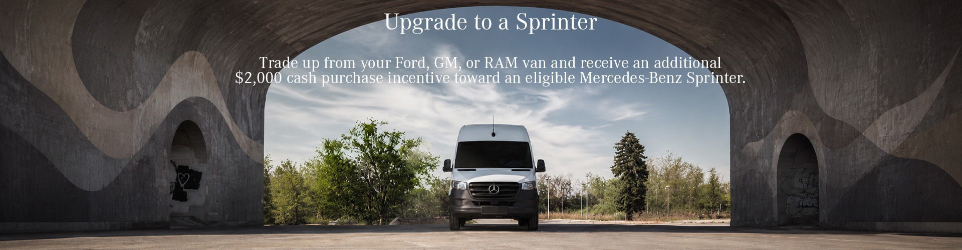 White Mercedes-Benz Sprinter van positioned under a concrete bridge with a trade-up incentive offer.