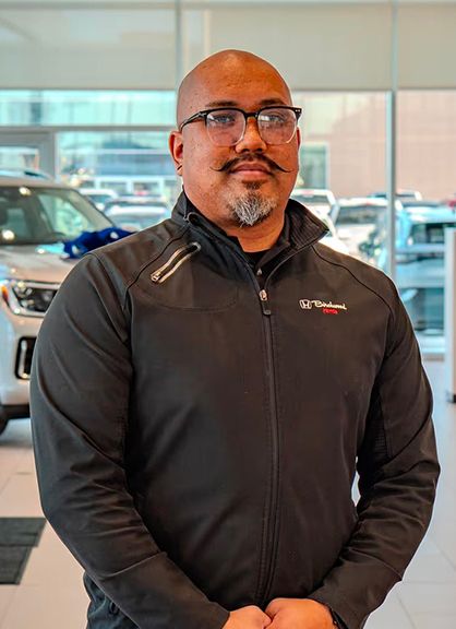 A man with glasses and a mustache wearing a Birchwood Honda jacket.