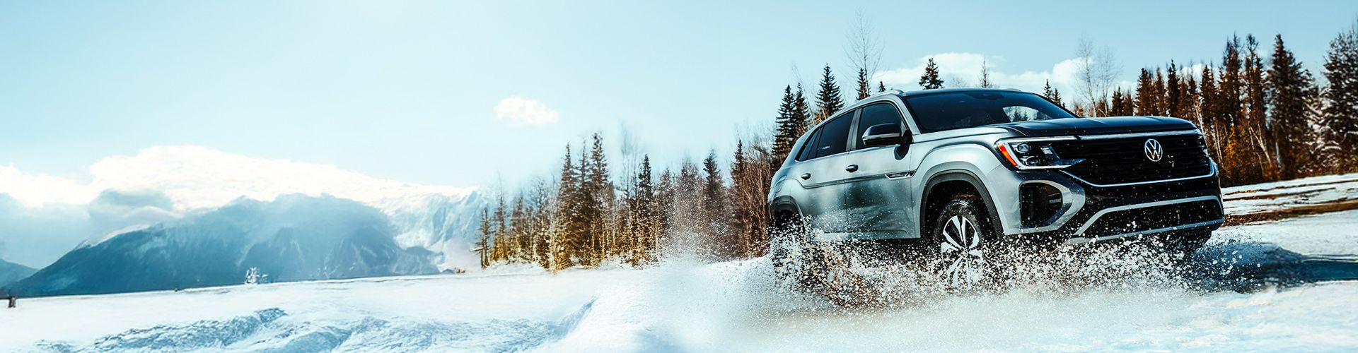 A silver Volkswagen SUV driving through a snowy landscape, kicking up a spray of snow from its wheels.