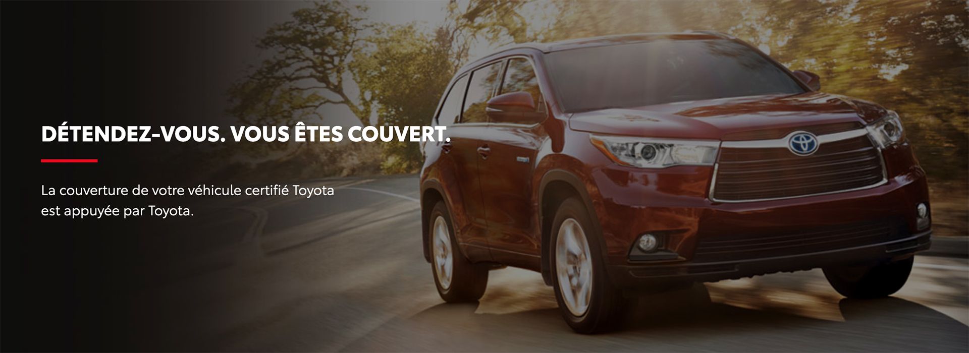 Un Toyota Highlander rouge roulant sur une route à côté d'un texte promotionnel en français sur une garantie certifiée : « DÉTENDEZ-VOUS. VOUS ÊTES COUVERT. »