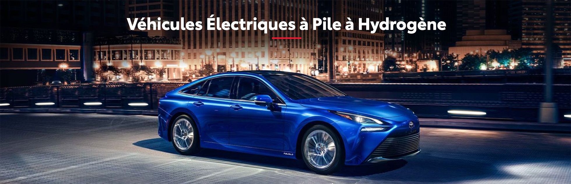 Voiture bleue (Toyota Mirai) à pile à hydrogène conduisant de nuit en ville. Texte: Véhicules Électriques à Pile à Hydrogène.