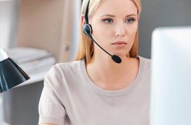 Femme avec un casque travaillant sur un ordinateur, probablement en service client.
