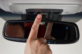 Doigt appuyant sur un bouton près du rétroviseur, probablement pour un service d'urgence ou d'assistance.