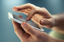 Gros plan sur des mains utilisant l'écran tactile d'un téléphone intelligent.