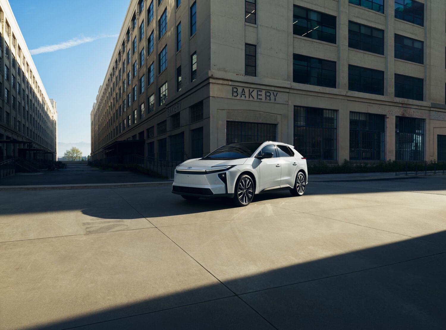 Une berline blanche roule à vive allure sur une route, avec des effets de flou de mouvement bleus.
