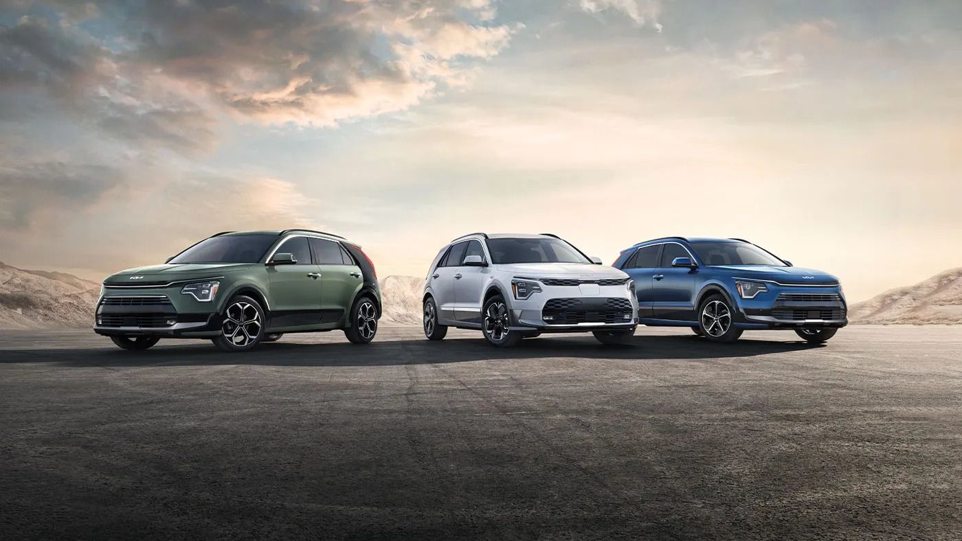 The rear view of a red sedan parked on the side of a rural road, with green hills in the distance.