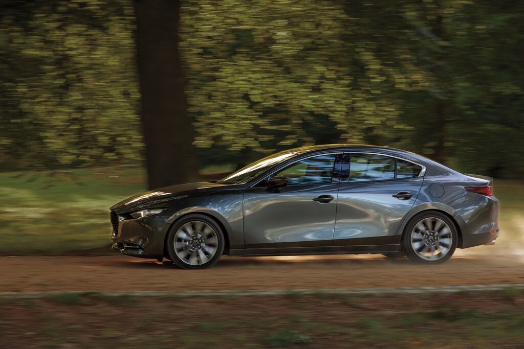 Mazda3 Berline 2025 en mouvement, vue latérale, conduite sur route bordée d’arbres
