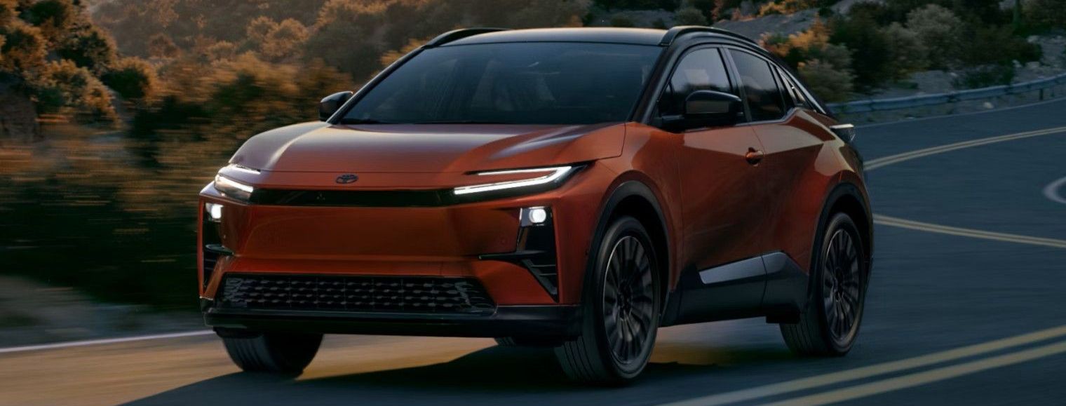 A smiling female salesperson and a male customer look at a clipboard together inside a bright car dealership showroom.