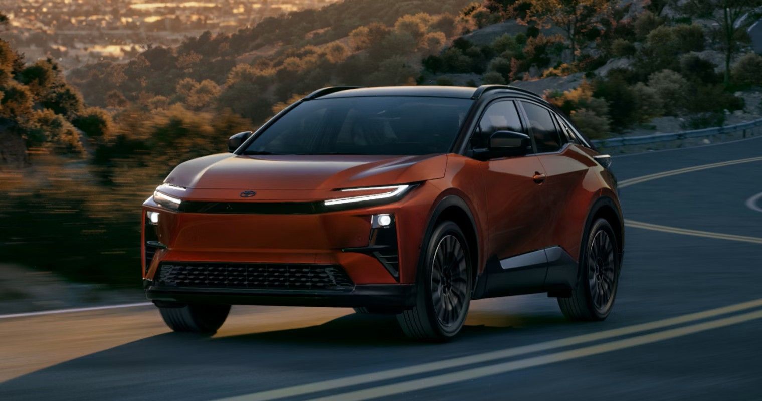Une vendeuse automobile souriante et un client masculin regardent ensemble un presse-papiers dans une salle d'exposition lumineuse.
