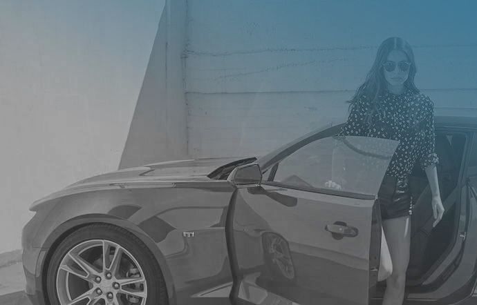 Stylish woman wearing sunglasses getting into a red sports car.