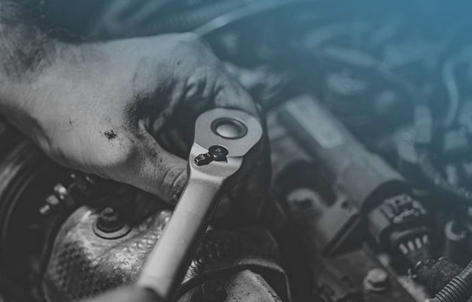 Gros plan sur les mains d'un mécanicien utilisant une clé à cliquet dans un moteur d'automobile.