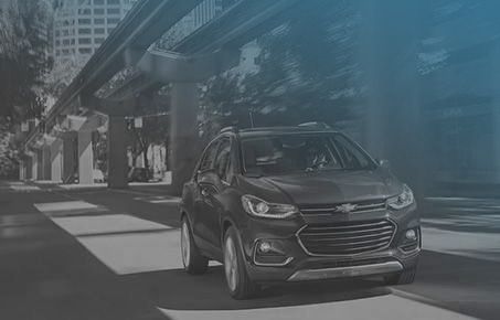 SUV Chevrolet foncé roulant sous une structure urbaine.