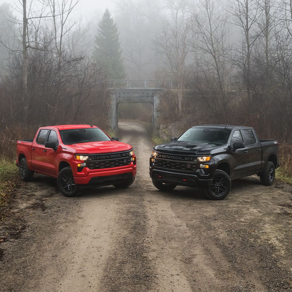 Smiling car salesman in a suit, holding a tablet in a dealership showroom.