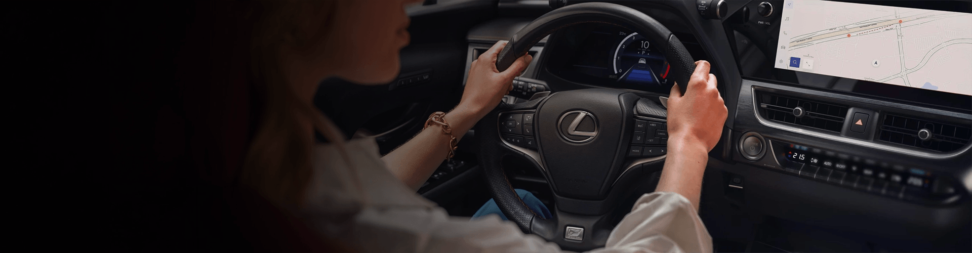 Une vue par-dessus l'épaule d'une femme au volant d'une Lexus dotée d'un tableau de bord numérique.