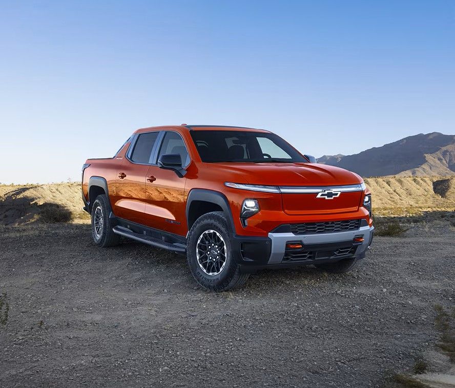 A smiling man sits in the driver's seat of a modern car, looking at his smartphone.