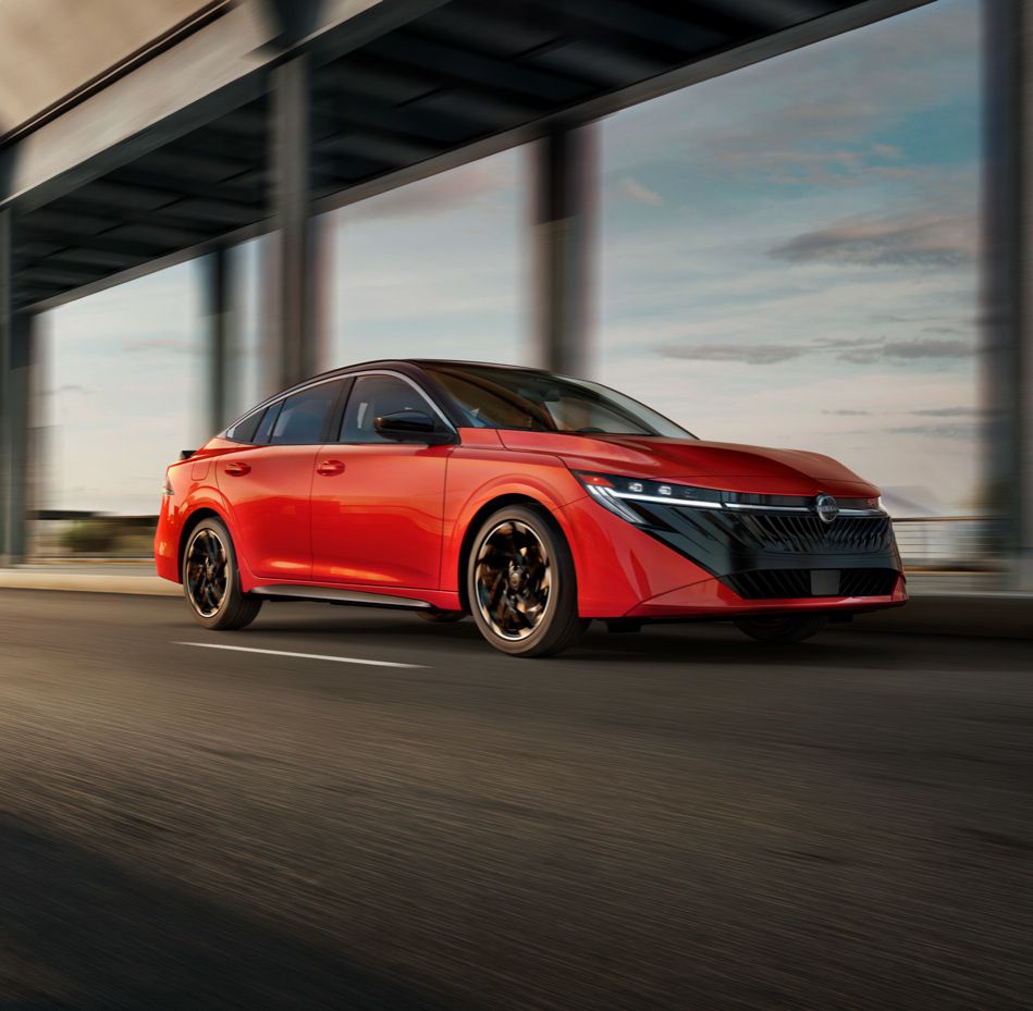 Bright red sports sedan in motion on a highway under an overpass.