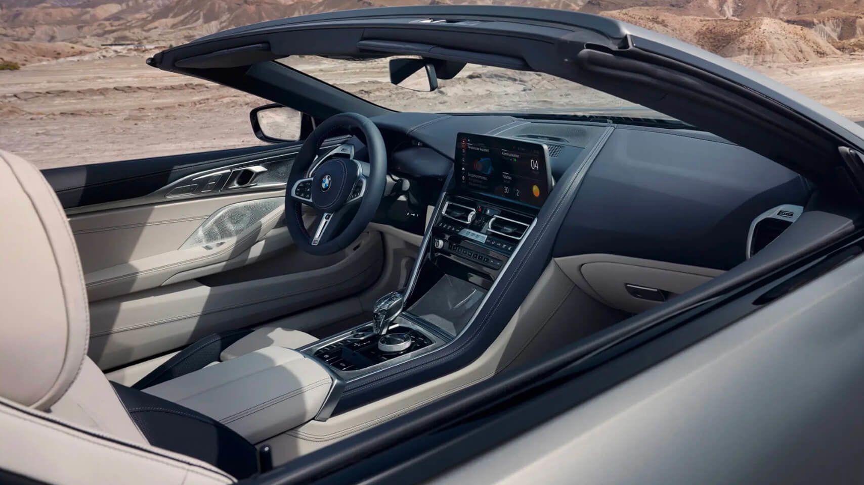 Interior view of a BMW 8 Series Convertible from the passenger side, showing the white leather and open top.