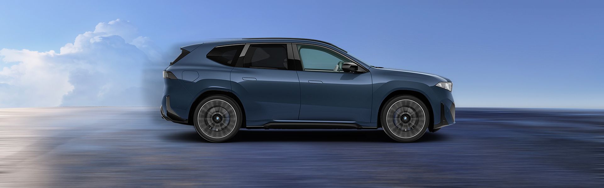 BMW i X3 50 bleu maue, de profil avec des nuages. 