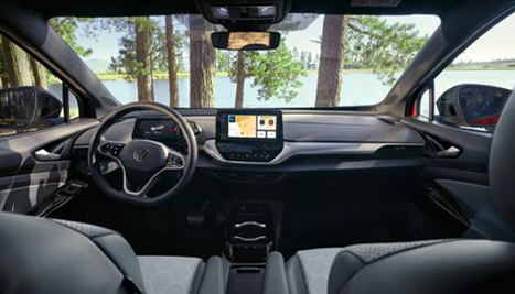 Habitacle moderne d'une Volkswagen ID.4 avec tableau de bord numérique et écran central, vue sur un lac et une forêt par le pare-brise.