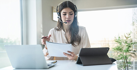 Femme professionnelle avec un casque d'écoute travaillant à un bureau, représentant le service client.