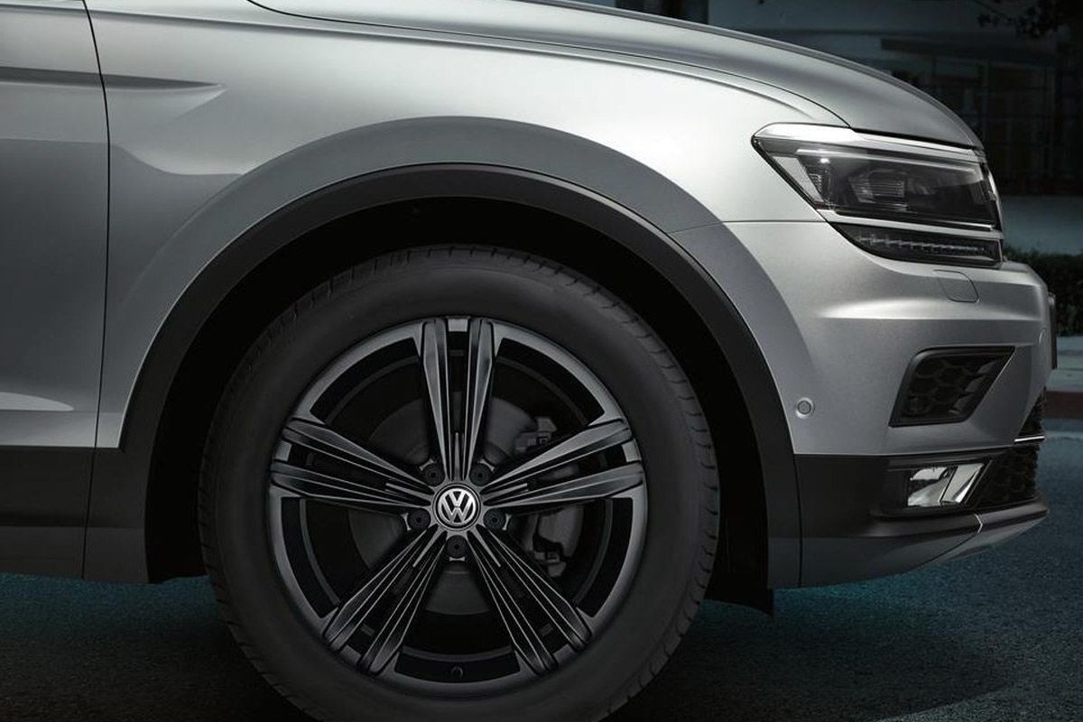 Vue rapprochée du quart avant d'un SUV Volkswagen argenté, mettant en évidence la roue en alliage noir et le phare moderne.