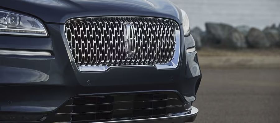 Front view close-up of a dark blue Lincoln SUV showcasing its signature chrome mesh grille and emblem