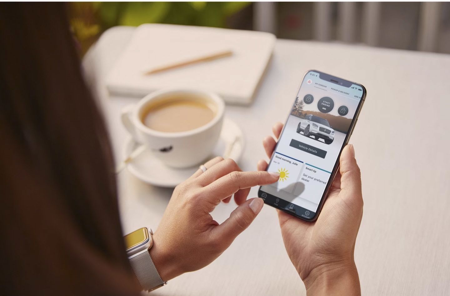 Woman holding a smartphone displaying the Lincoln Way app interface next to a cup of coffee