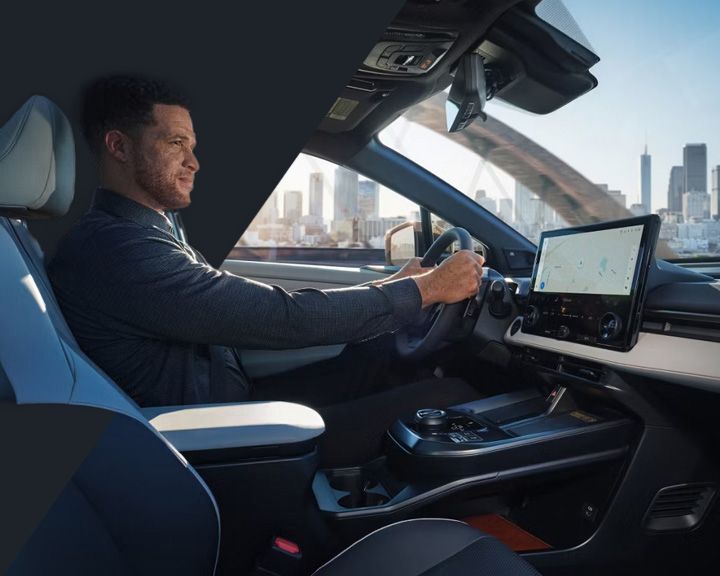 Un homme au volant d'une Toyota dotée d'un grand écran tactile affichant une carte de navigation.