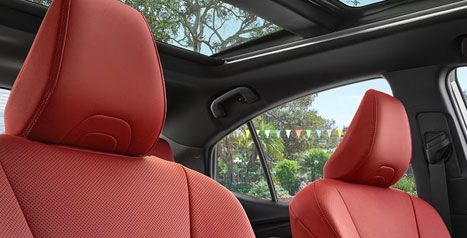 Vue de l'intérieur d'un véhicule Toyota montrant des sièges sport en cuir rouge et un toit ouvrant panoramique, soulignant la structure de sécurité de l'habitacle.