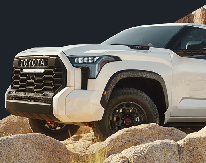 Gros plan d'un Toyota Tundra TRD Pro blanc en conduite hors route sur un terrain rocheux.